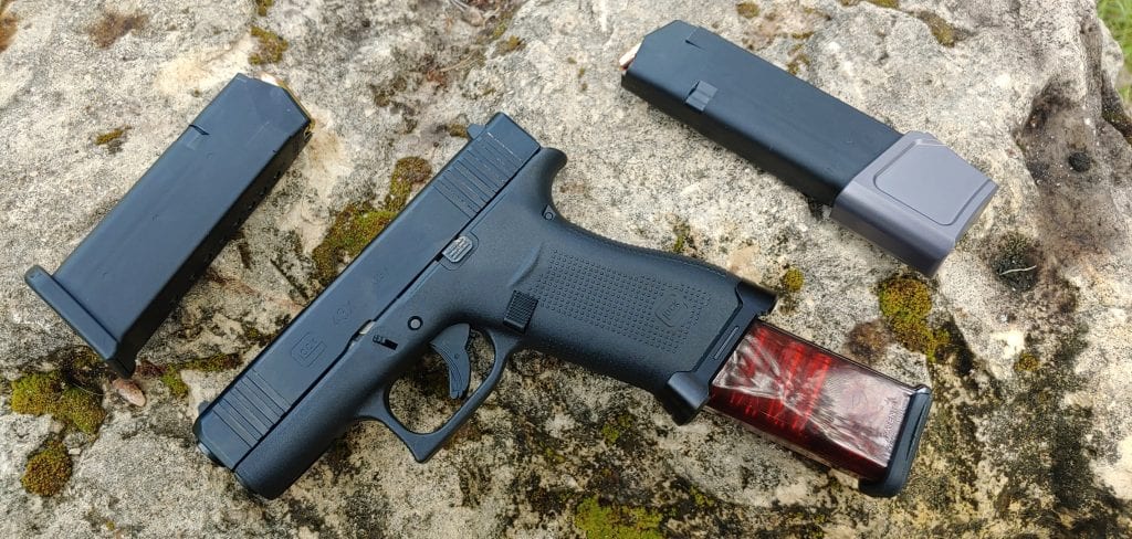 Glock 43X loaded with red ETX extended magazine, OEM magazine, and G43X magazine with Tyrant Designs magazine extension