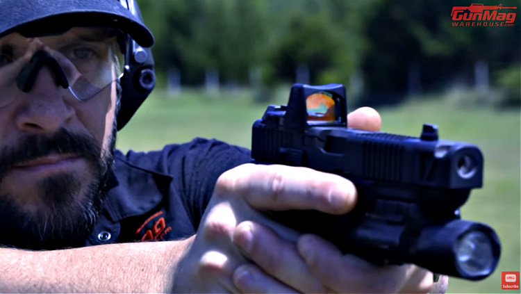 Daniel Shaw, gun training instructor, looking through a red dot optic