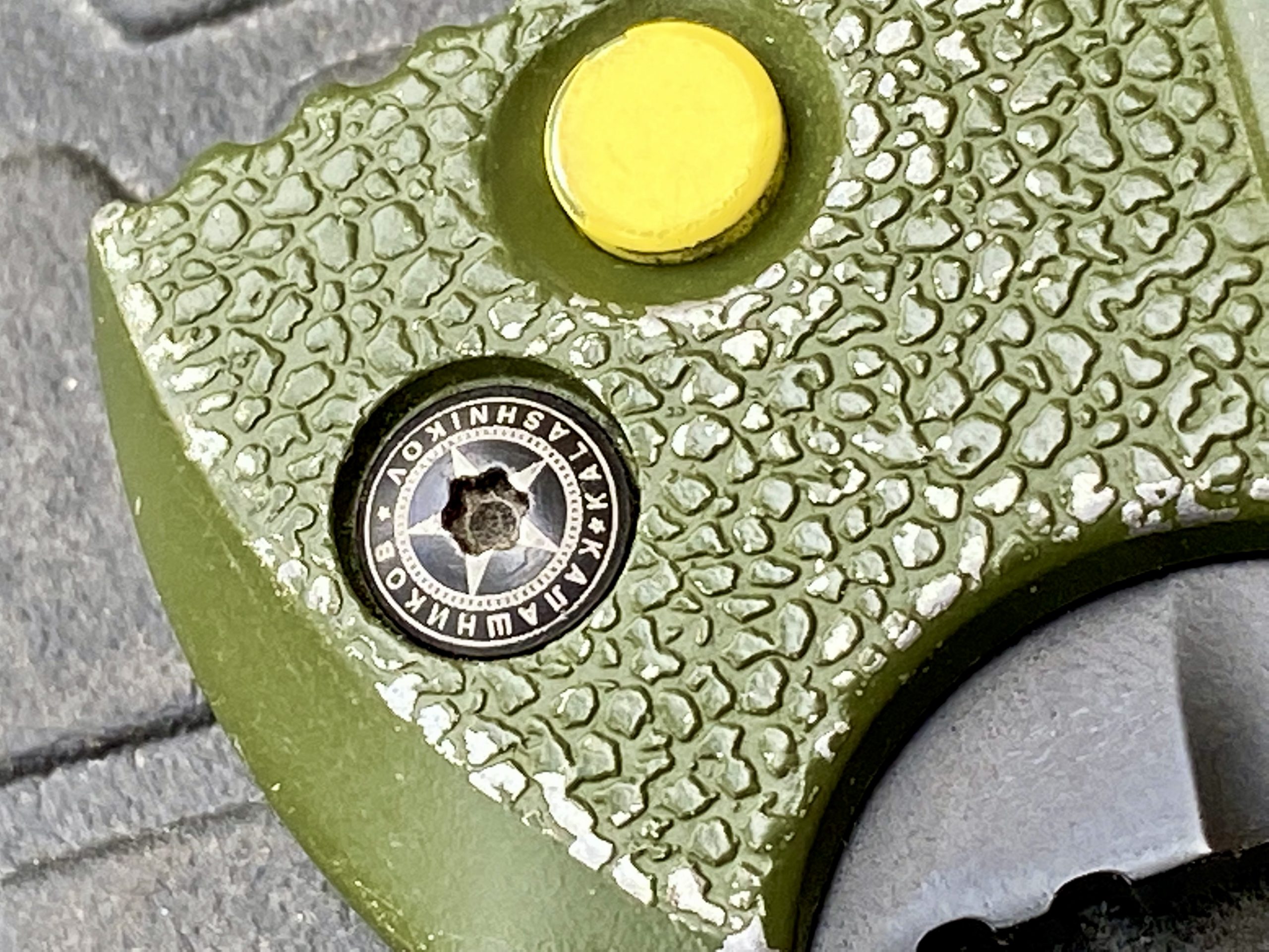 O botão para travar e soltar nesta versão é amarelo brilhante.  A textura de seixos na alça adiciona um pouco de aderência ao alumínio liso.