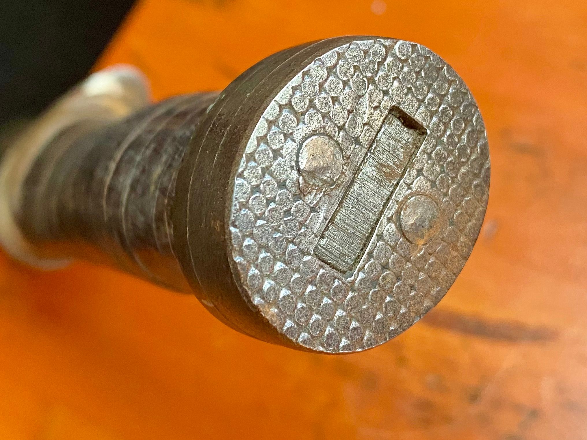 The pommel could be used as a hammer. It is stout. It also looks like a division sign. The two nails link the three pieces of steel together.