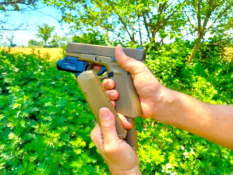 tactical reload of Glock 19x with empty magazine between thumb and forefinger of supporting hand