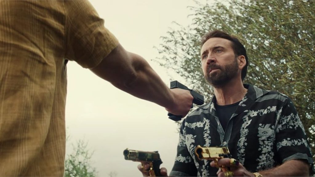Nicolas Cage holding pistols in The Unbearable Weight of Massive Talent