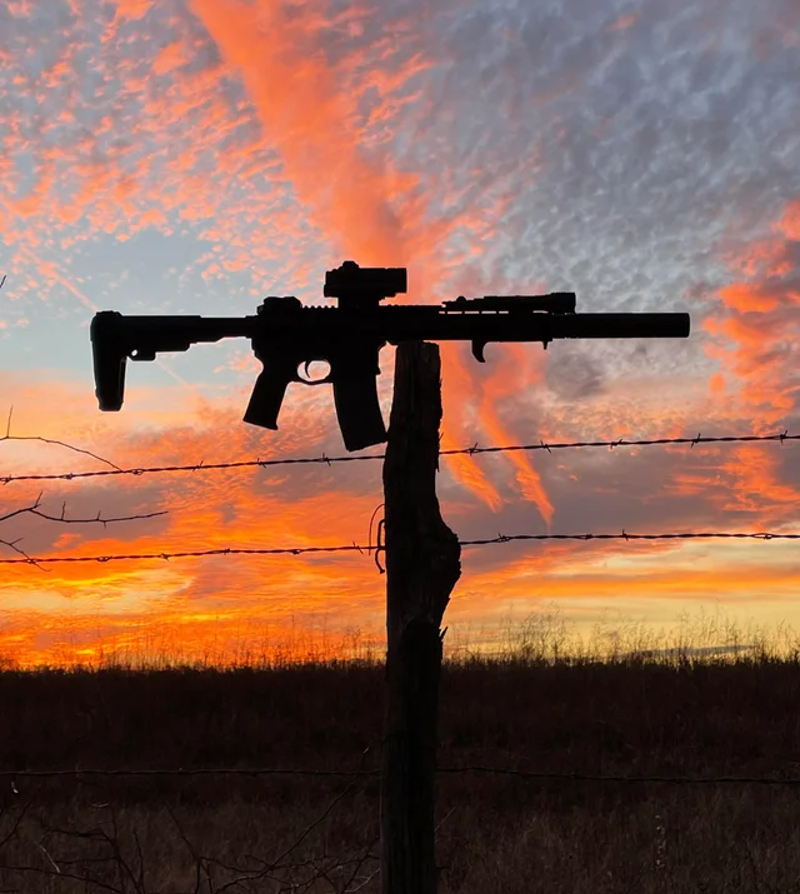 AR-15 on fencepost silhouette with sunset