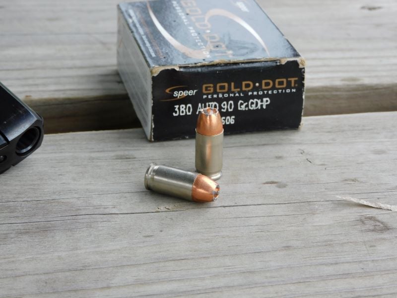 Two complete 380 ACP Speer Gold Dot rounds positioned in front of a black factory box.