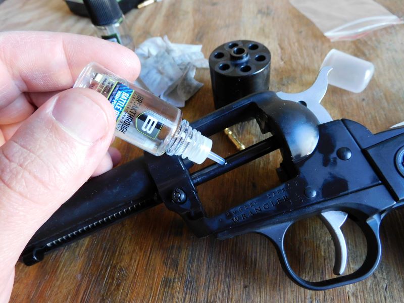 The author squeezes a bottle of oil against a cylinder pin of a revolver.
