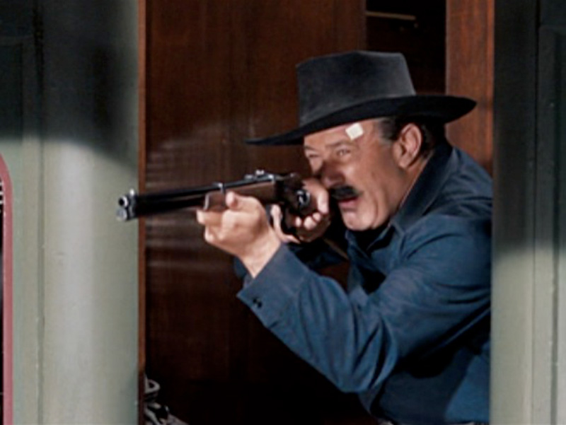 Lou aiming a winchester rifle on a train in How the West Was Won movie