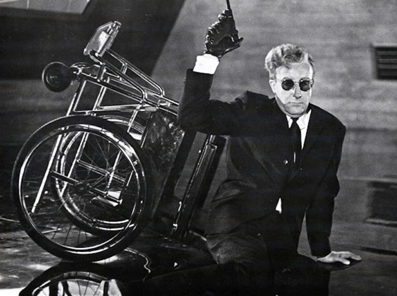 Dr. Strangelove fallen from his wheelchair holding his luger up in the air with his 'alien hand'