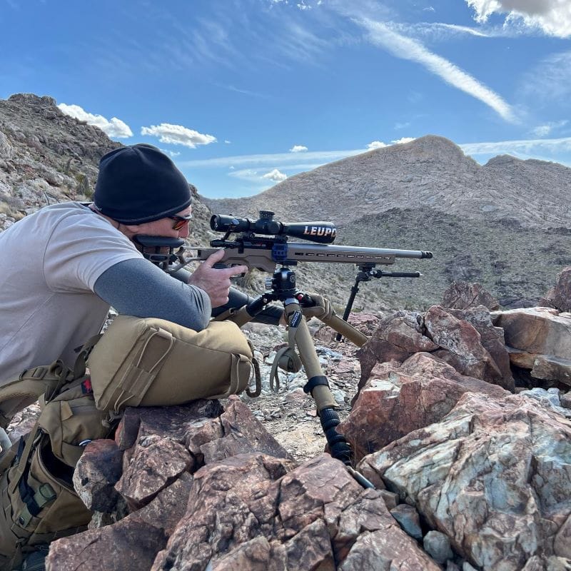 shooter on rocks using a tripod to shoot off of