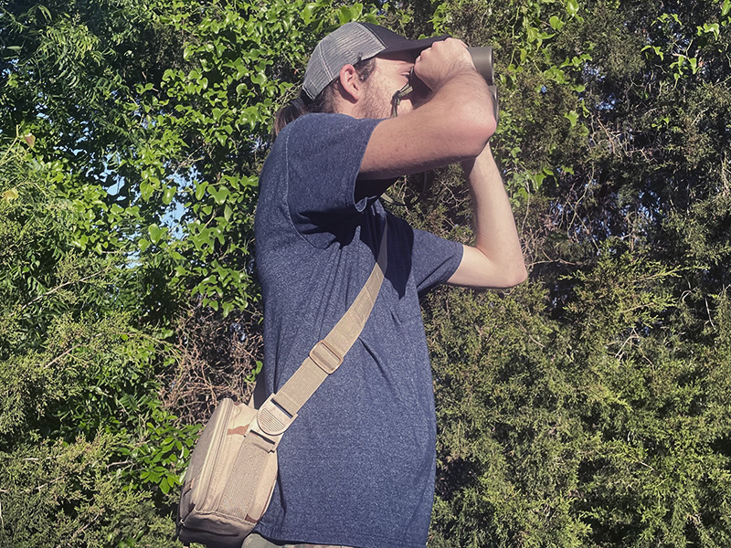 Man looking through binoculars in the woods