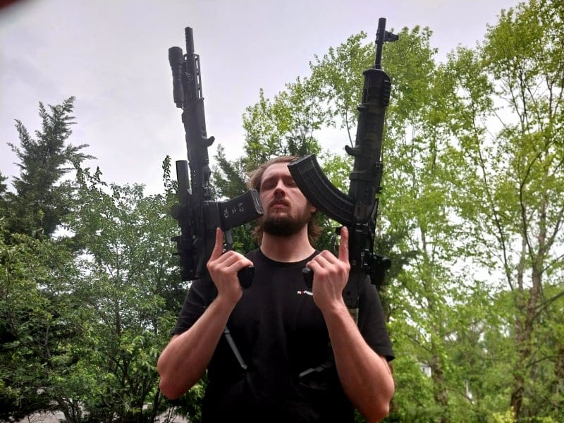 man holding an AR and an AK. Which is better?