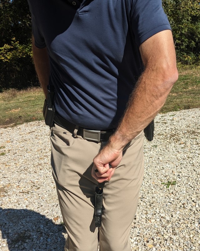 Gun held between legs with shooter putting magazine into gun