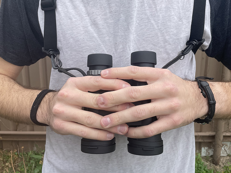 binos in hands at chest level with chest harness