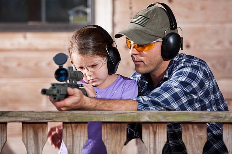 father and daughter shooting rifle; gun safety